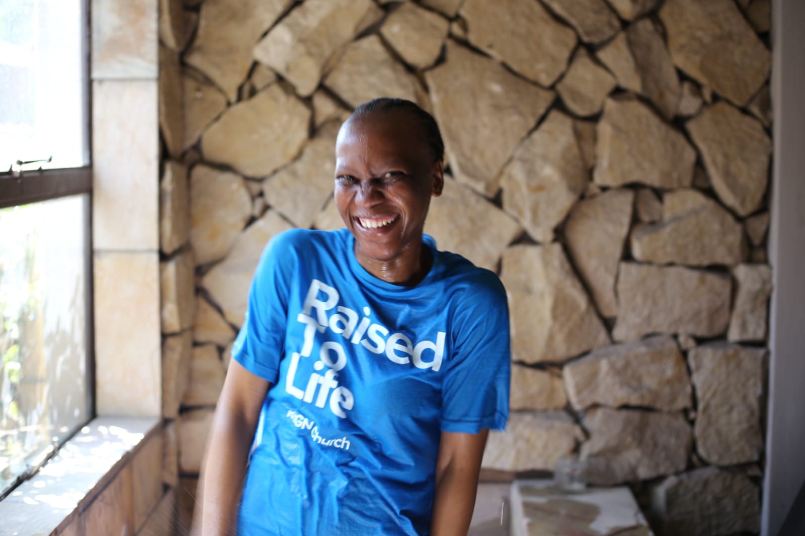 New believer baptised at REIGN Church wearing a 'Raised To Life' shirt