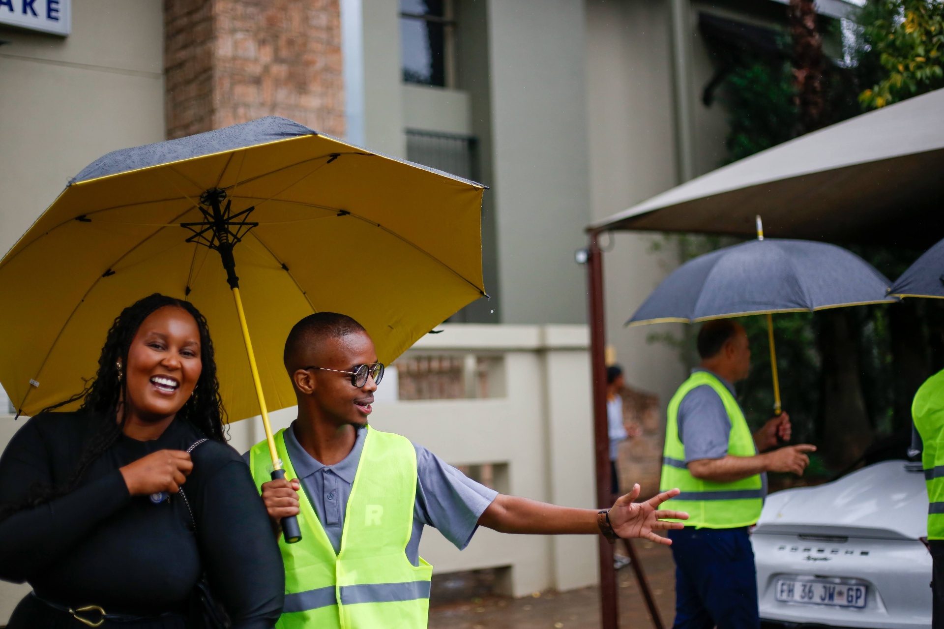 REIGN Church Serve Team welcoming guests in the rain with umbrellas